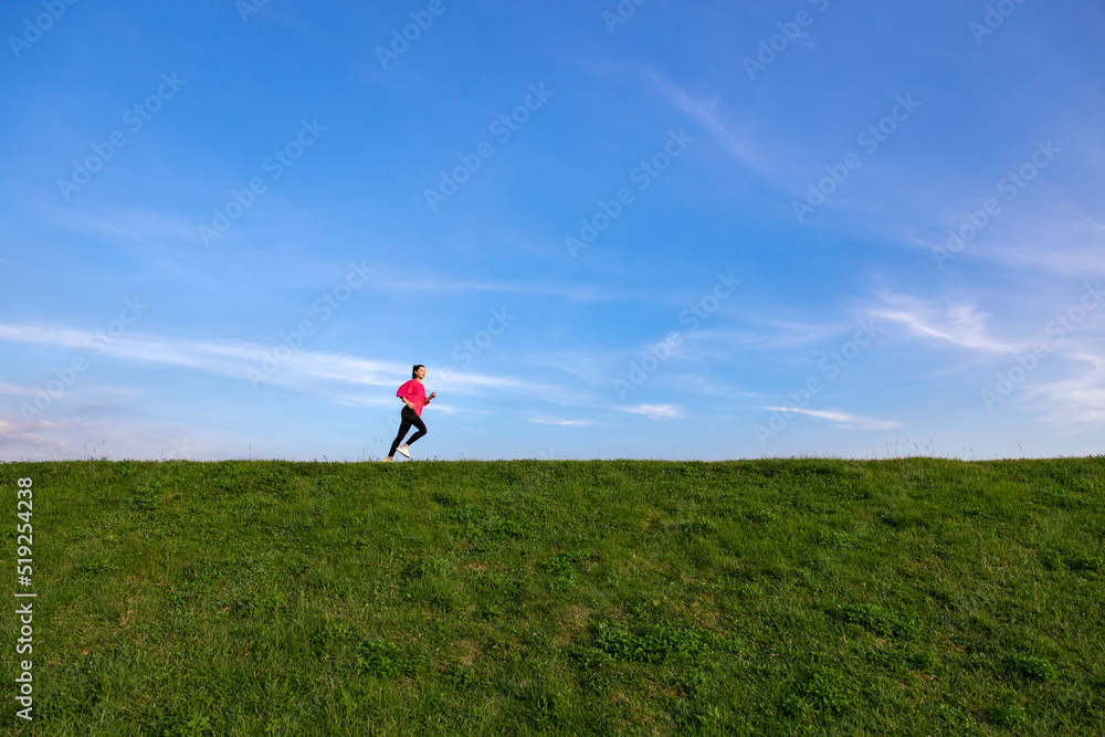 Young Asian girls jogging for fitness in the open grass Young Asian girls jogging for fitness in the open grass