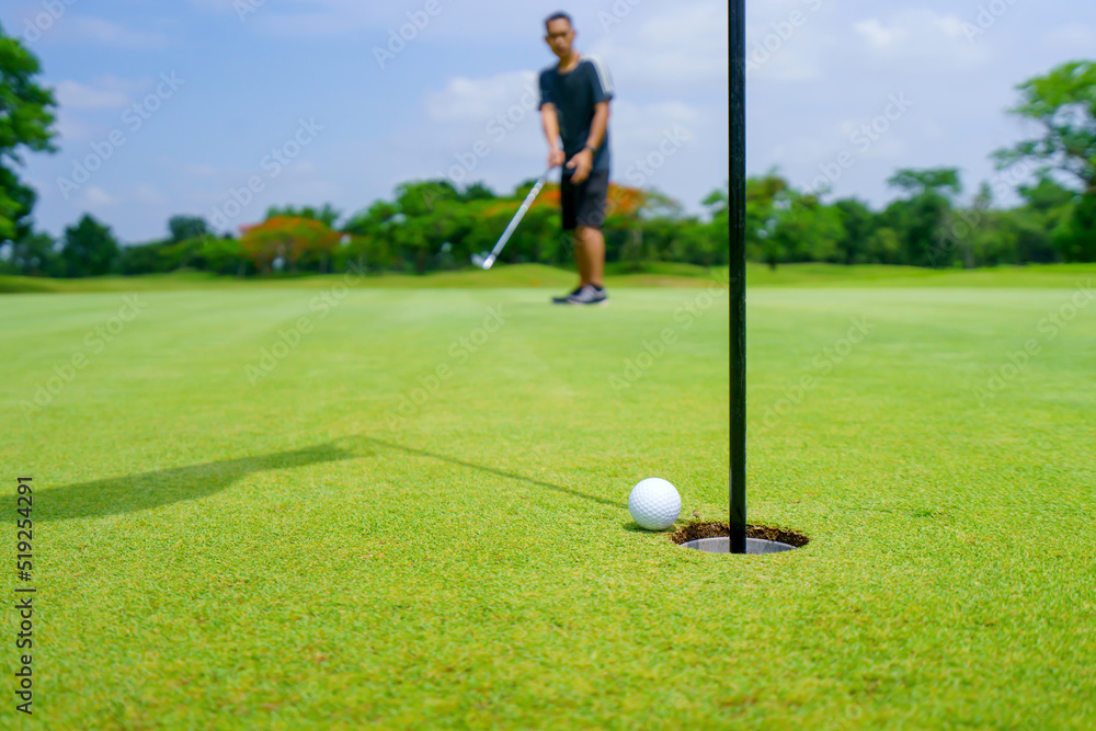 Obraz premium Golfer putt golf ball into hole on the green at golf course