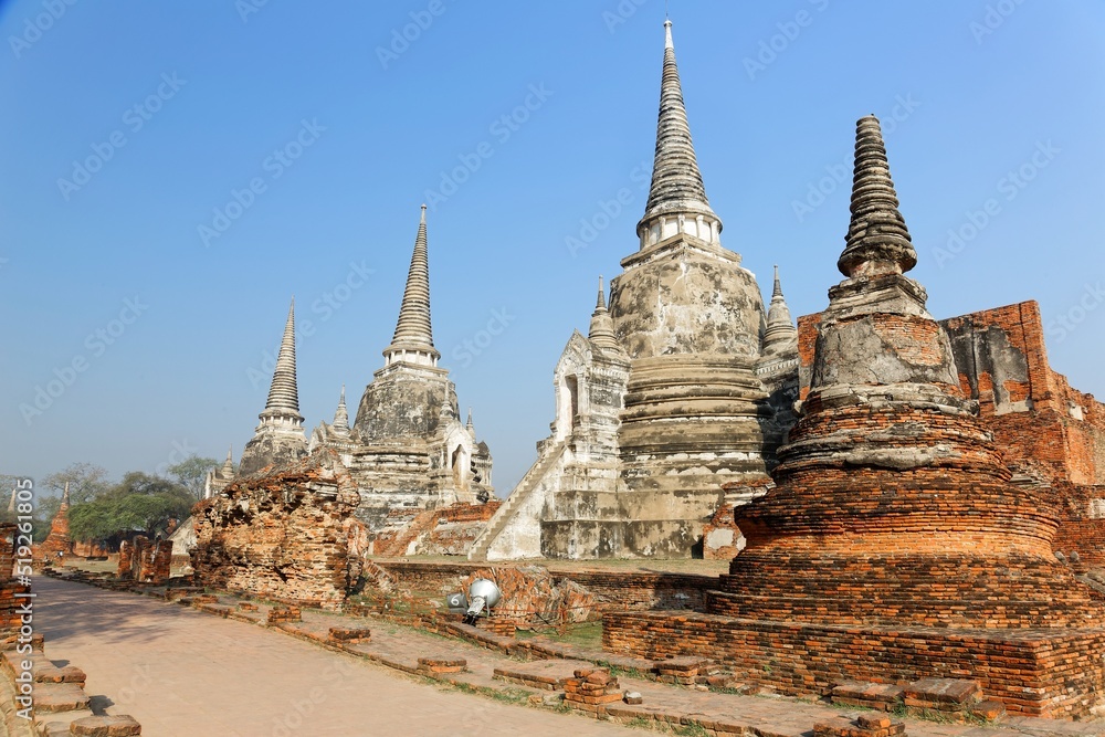 Fototapeta premium Ruined stupas of an ancient Buddhist temple under bright sunshine in Ayutthaya Historical Park, Thailand ~ Wat Phra Si Sanphet is one of Ayuthaya's best known temples and a major tourist attraction