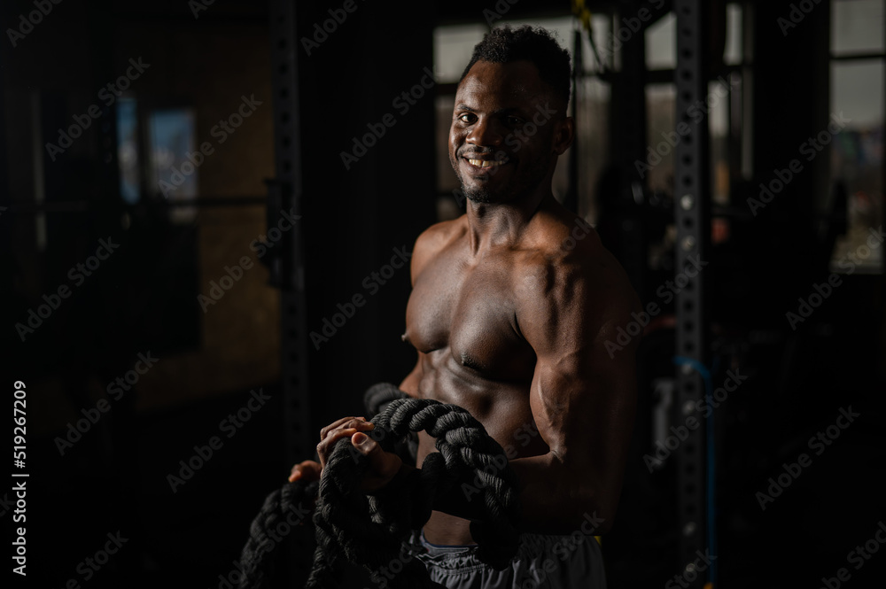 Muscular african american man posing with rope in gym. Muscular african american man posing with rope in gym.