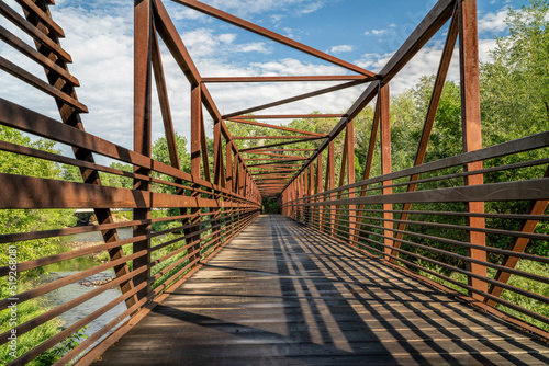 Fotografiet bike trail and a long footbridge over a river - Cache la Poudre River in Fort Co