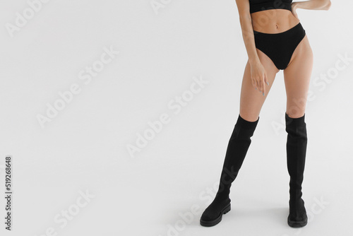 Tanned slim legs of a woman on white studio background. Close up of fitness model in sports clothing. Underpants or underwear advertising. Skin care or diet banner