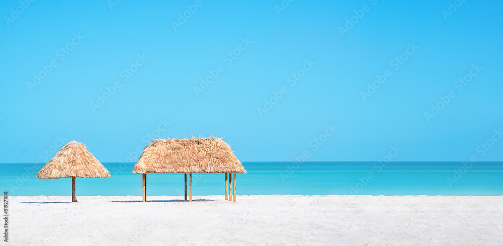 Beach Umbrella made of palm leafs on a perfect white beach in front of Sea. The right place for relax and vacations