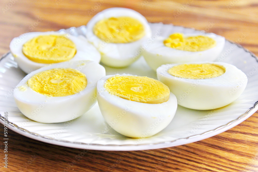 Half boiled eggs laid out in white plates and served on a wooden table. Half boiled eggs laid out in white plates and served on a wooden table.