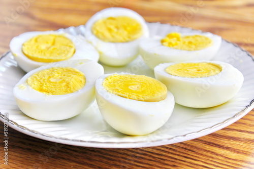 Half boiled eggs laid out in white plates and served on a wooden table.