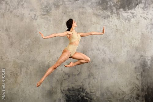 Graceful ballerina jumping in studio