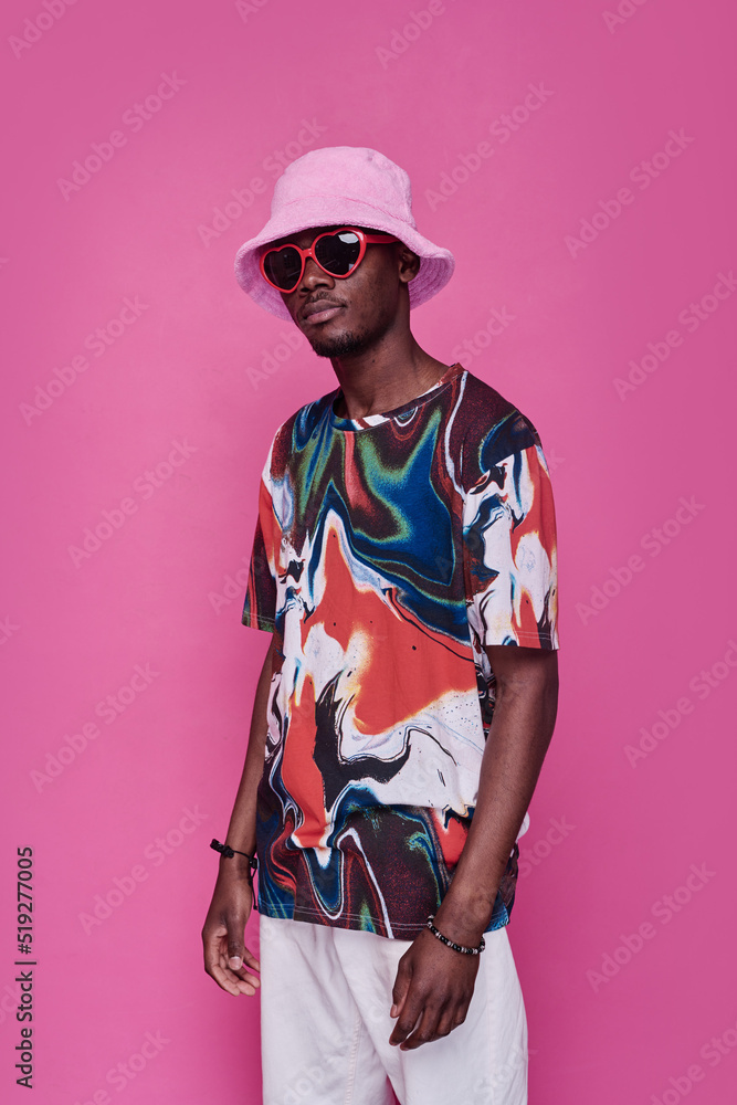 Portrait of African teenager in trendy panama hat and sunglasses standing against pink background Portrait of African teenager in trendy panama hat and sunglasses standing against pink background