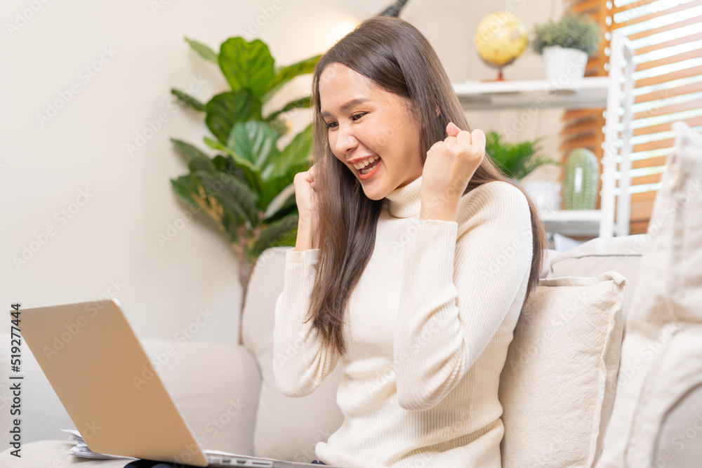 Happy cheerful, satisfied asian young freelancer woman, girl sitting on sofa or couch, using laptop computer in living room at home, looking and smiling at screen, entrepreneur enjoying with work, wfh Happy cheerful, satisfied asian young freelancer woman, girl sitting on sofa or couch, using laptop computer in living room at home, looking and smiling at screen, entrepreneur enjoying with work, wfh