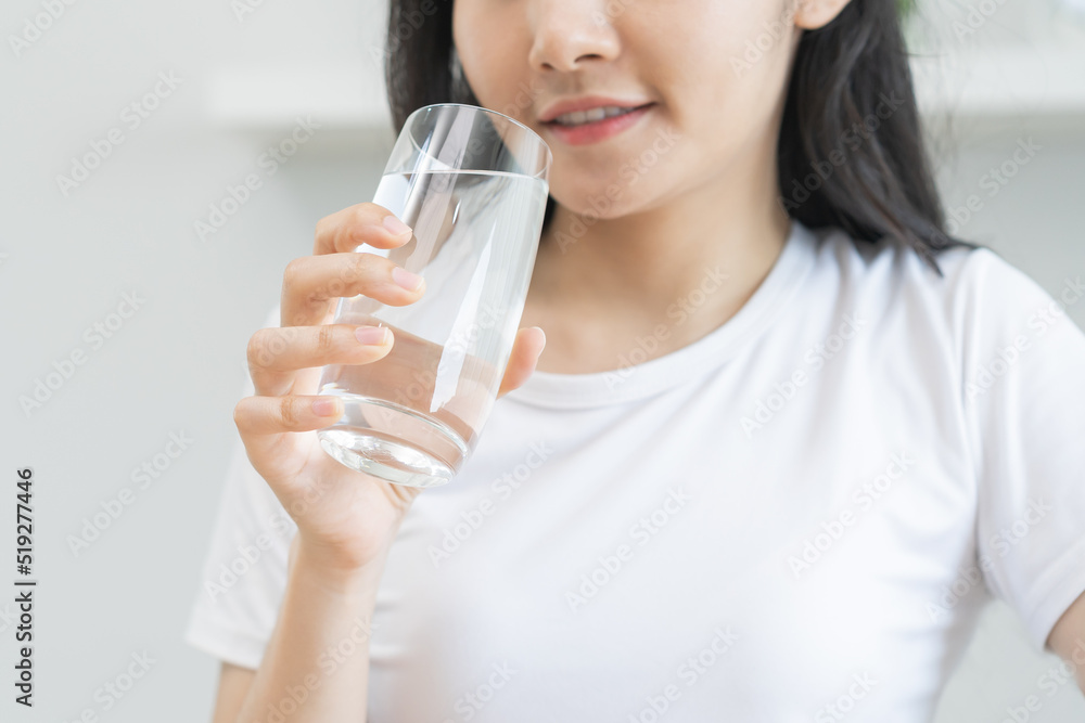 Happy beautiful, asian young woman hand in holding, drinking fresh glass of water for hydration of body, holding transparent glass in her hand, thirsty at home. Health care, healthy lifestyle concept. Happy beautiful, asian young woman hand in holding, drinking fresh glass of water for hydration of body, holding transparent glass in her hand, thirsty at home. Health care, healthy lifestyle concept.