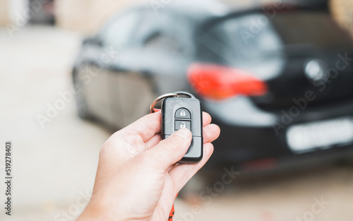 Human caucasian hand using car remote key pressing button, closeup. Car security alarm concept