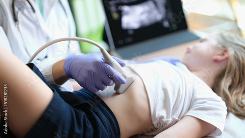 Physician examines with ultrasound of internal organs of child in clinic