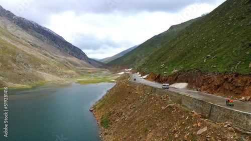 Wide drone shot of the Babusar Pass mountain pass in Pakistan, with a few vehicles on the road in the Kaghan Valley photo