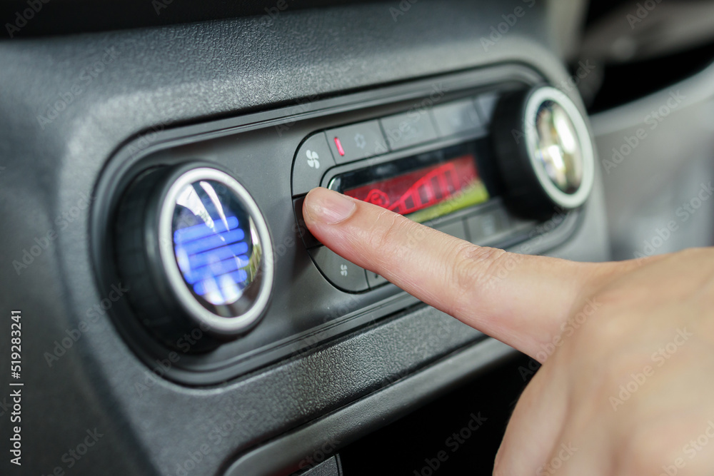 Woman hand turn on car air conditioning system Woman hand turn on car air conditioning system