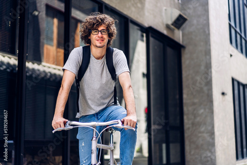 Portrait of casual hipster handsome businessman with backpack looking forward while commuting riding bicycle on the street city way go to work.business travel transport bike concept