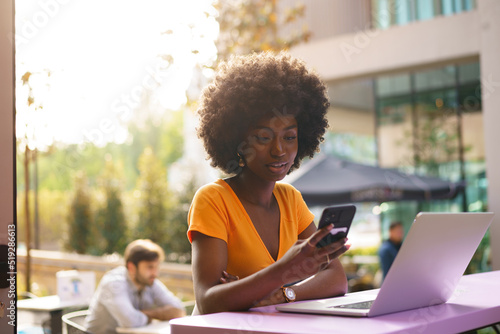 Happy beautiful young black woman using laptop in cafe