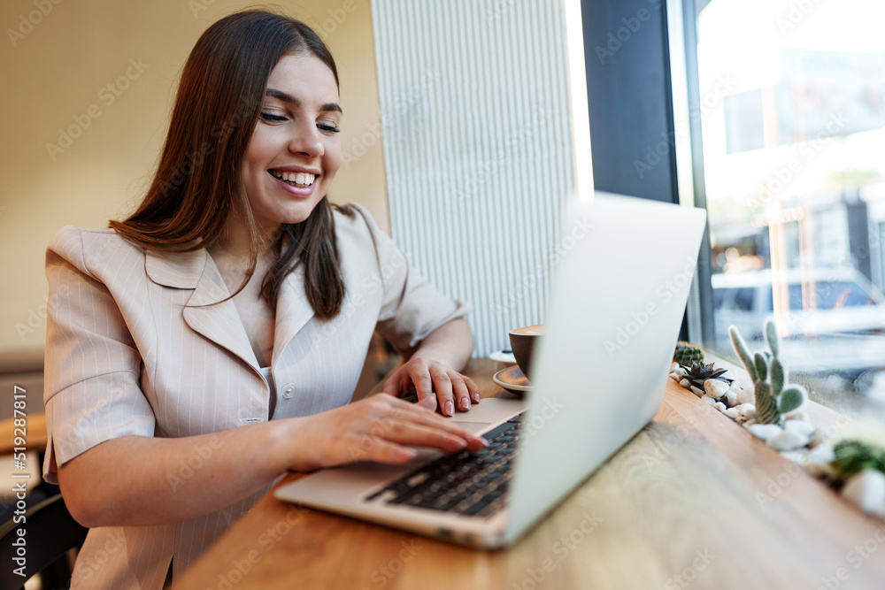 Young businesswoman using a laptop during a coffee break in coffeeshop Young businesswoman using a laptop during a coffee break in coffeeshop
