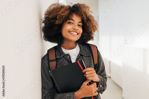 Canvas Print Portrait of a beautiful female college student leaning a wall and looking at cam