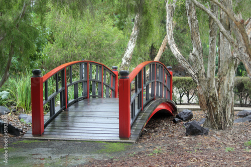 Fotografiet Red wooden bridge and a tree in a garden