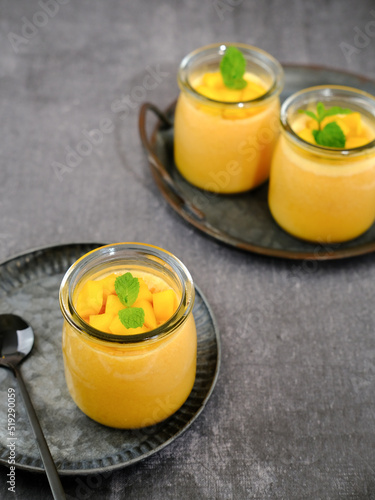 Mango pudding topped with mango chunks and mint leaf garnish. Served in a jar, fresh and healthy
 photo