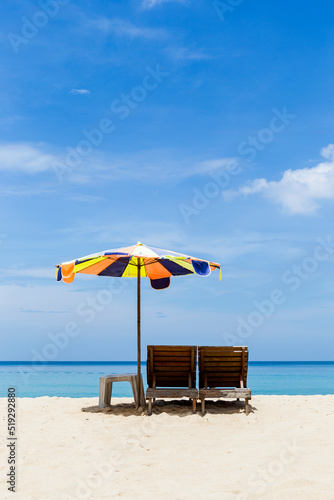 Colorful beach umbrella and wooden chair on beautiful beach, tropical summer background, holiday and vacation destination, beach in south of Thailand