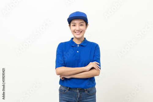 Happy delivery asian woman in blue uniform standing on isolated white background. Smiling female delivery service worker. © Chanakon