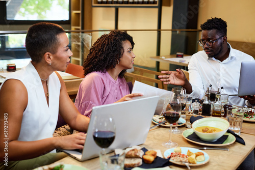 Businesspeople sit at the dinner table in a restaurant and brainstorm about a start-up project.