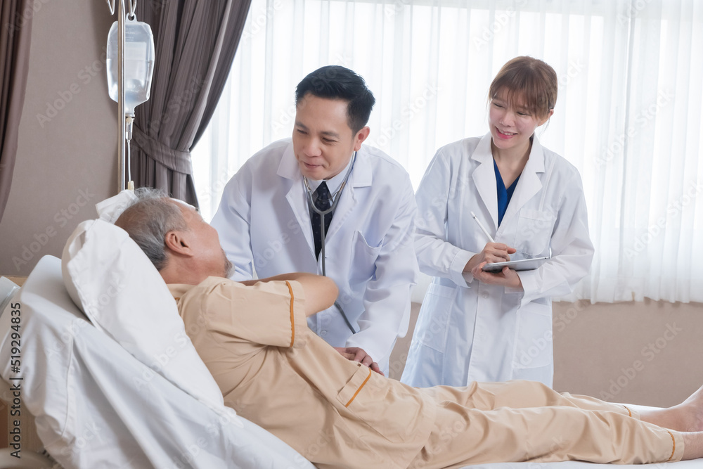 Asian doctor and nurse visit and take care senior man patient in room. Attractive two therapist practitioner explain diagnosis in hospital ward to treatment to elderly older male during appointment. Asian doctor and nurse visit and take care senior man patient in room. Attractive two therapist practitioner explain diagnosis in hospital ward to treatment to elderly older male during appointment.