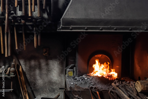 Close up view of heated metal and fire oven. Blacksmith in the production process of other metal products handmade in the forge. Metalworker forging metal into knife. Metal craft industry.