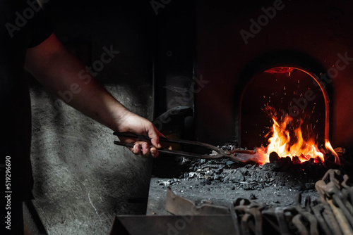 Close up view of heated metal and fire oven. Blacksmith in the production process of other metal products handmade in the forge. Metalworker forging metal into knife. Metal craft industry.