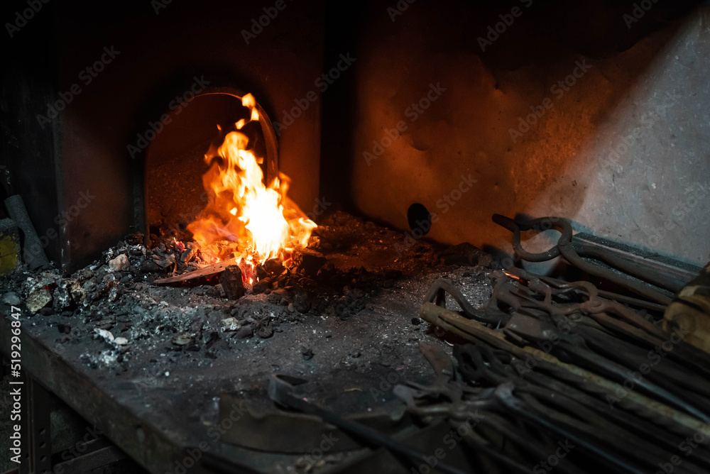 Close up view of heated metal and fire oven. Blacksmith in the production process of other metal products handmade in the forge. Metalworker forging metal into knife. Metal craft industry. Close up view of heated metal and fire oven. Blacksmith in the production process of other metal products handmade in the forge. Metalworker forging metal into knife. Metal craft industry.