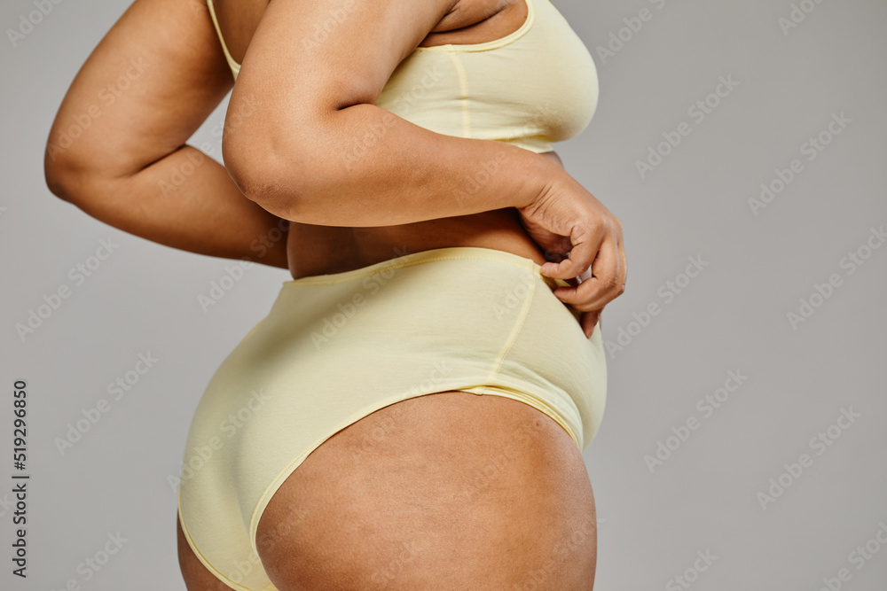 Minimal closeup of unrecognizable black woman wearing underwear against  grey background, focus on hips and cellulite, body positivity Stock Photo