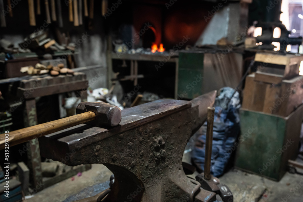 Close up view of heated metal and anvil. Blacksmith in the production process of other metal products handmade in the forge. Metalworker forging metal with a hammer into knife. Metal craft industry.