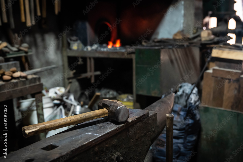 Close up view of heated metal and anvil. Blacksmith in the production process of other metal products handmade in the forge. Metalworker forging metal with a hammer into knife. Metal craft industry.