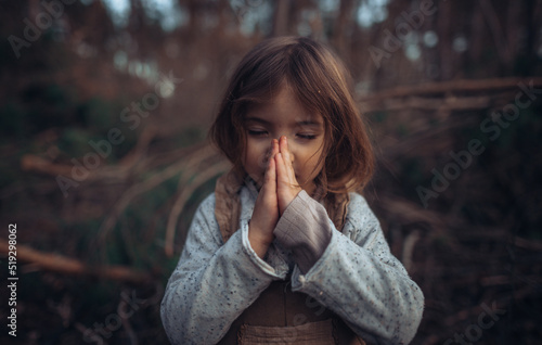 Photography Happy little girl with closed eyes praying in autumn forest.