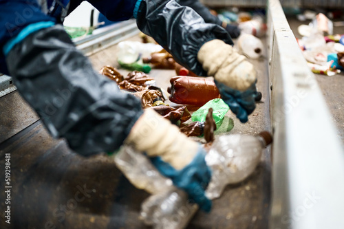 Worker sorts trash on conveyor belt at waste recycling plant