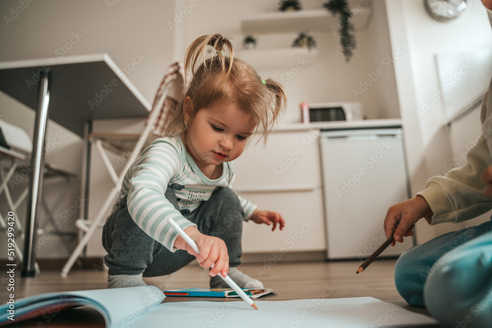 Two children playing on the kitchen floor Two children playing on the kitchen floor