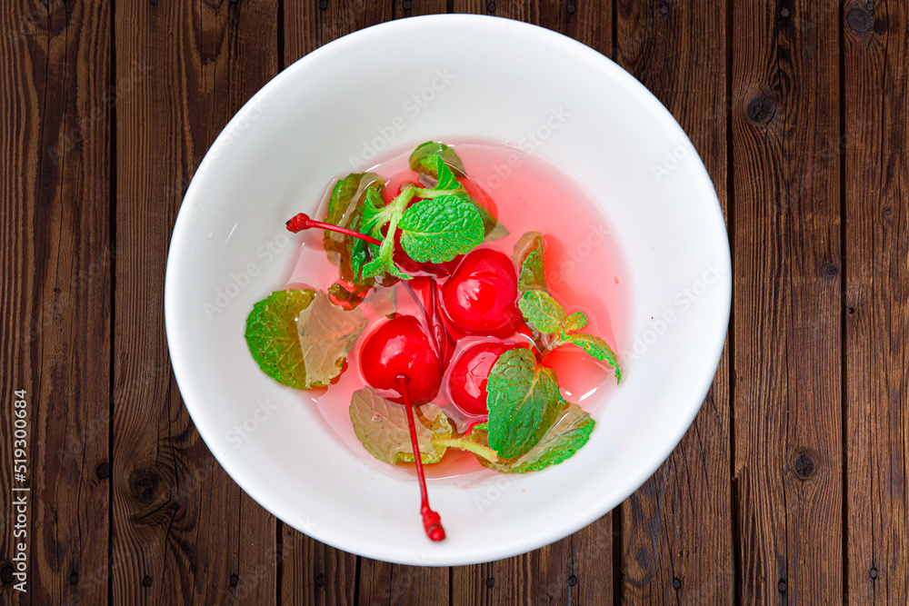 red cherry with green leaf in a white bowl red cherry with green leaf in a white bowl
