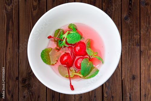 red cherry with green leaf in a white bowl
