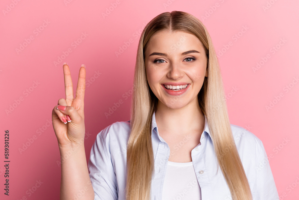 Photo of young cheerful girl show peace cool v-symbol travel trip hello isolated over pink color background Photo of young cheerful girl show peace cool v-symbol travel trip hello isolated over pink color background