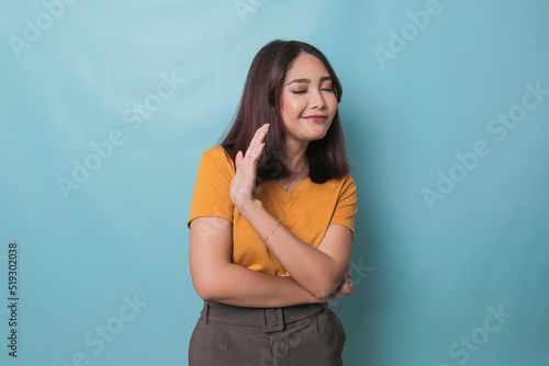 Stop. Concerned Asian woman showing refusal sign, saying no, raise awareness, standing over blue background photo