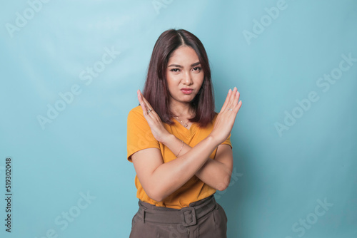 Stop. Concerned Asian woman showing refusal sign, saying no, raise awareness, standing over blue background