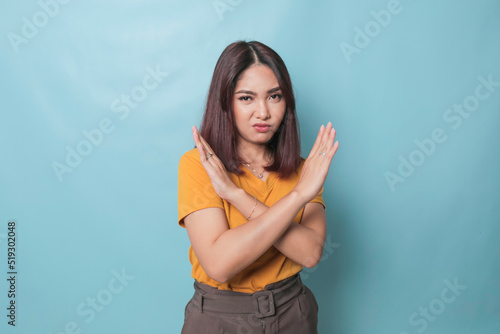 Stop. Concerned Asian woman showing refusal sign, saying no, raise awareness, standing over blue background photo