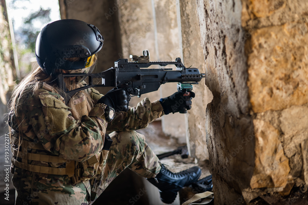 Fototapeta premium A woman in an army uniform shoots a firearm in an abandoned building. 