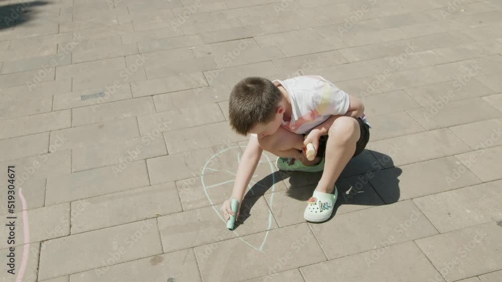 4K. A boy draws with colored crayons on the asphalt 4K. A boy draws with colored crayons on the asphalt