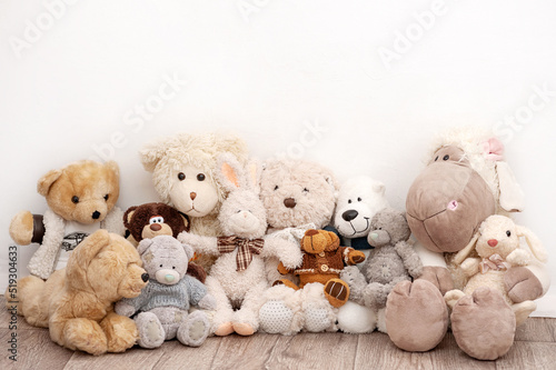 Many soft toys are sitting on the background of a white wall photo