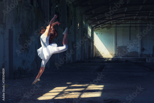 Ballerina dancing and jumping in abandoned building on a sunny summer day