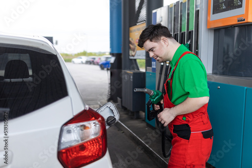 Down syndrome man employee fueling car at gas station. © Halfpoint
