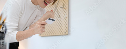Shot of excited young woman holding credit card and using laptop for shopping online.