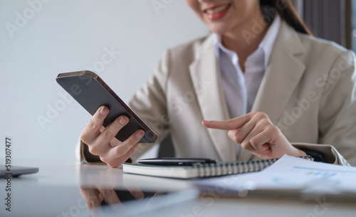 Smiling female employee checking social media, chatting on smart phone.