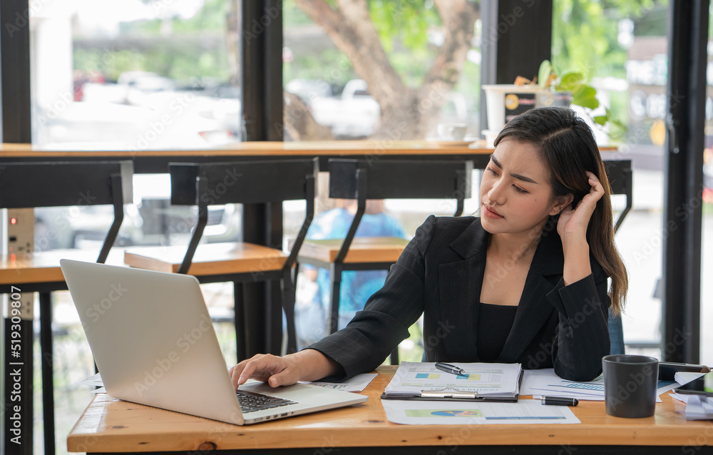Thoughtful Asian businesswoman in tension and looking for problem solution sitting at workplace desk while working on a laptop in an office. Thoughtful Asian businesswoman in tension and looking for problem solution sitting at workplace desk while working on a laptop in an office.